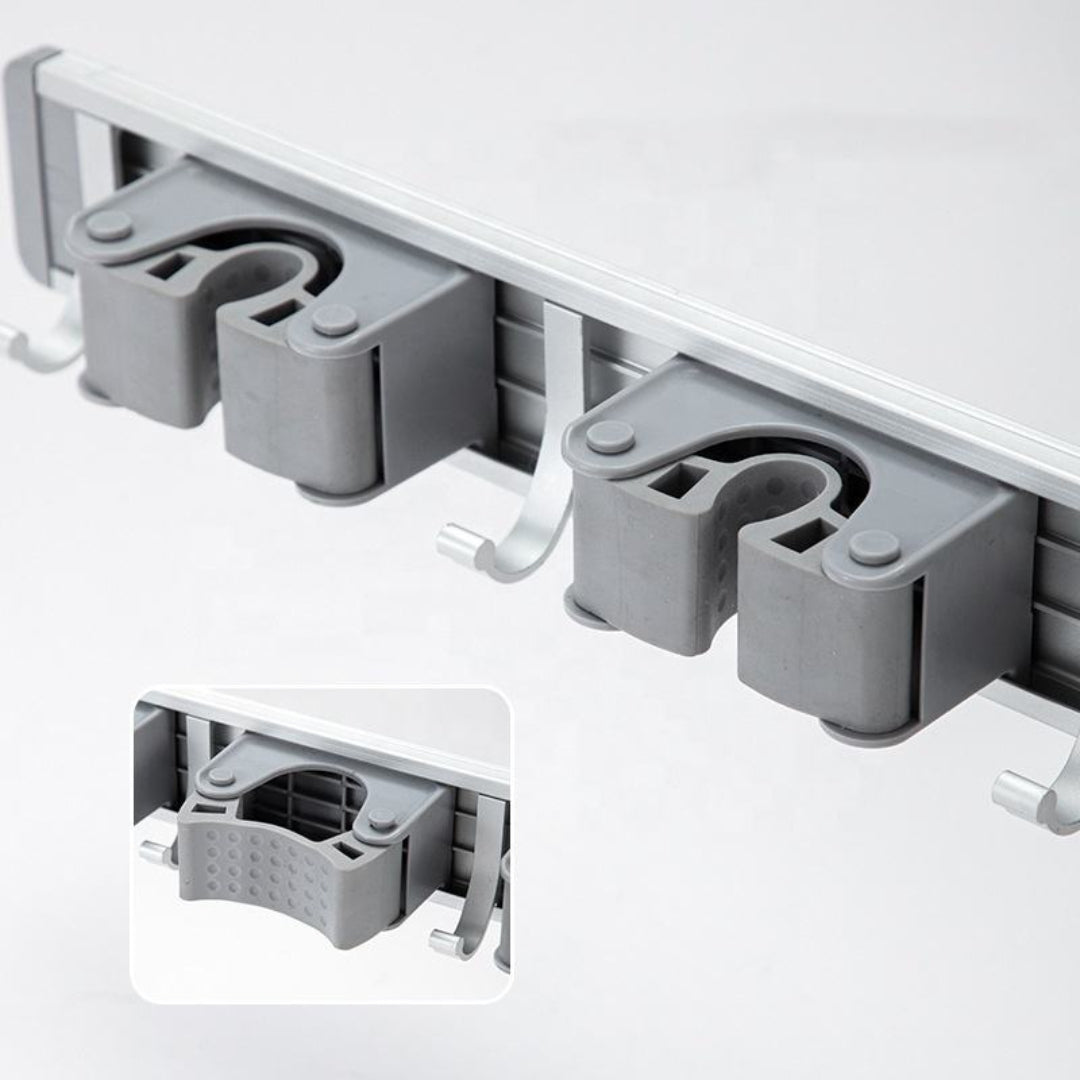 Close-up of anti-slip grip slots and hooks on wall-mounted mop and broom holder