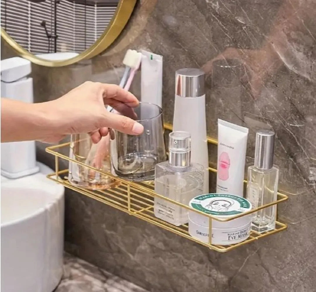 Gold bathroom wall shelf holding toiletries beside wash basin