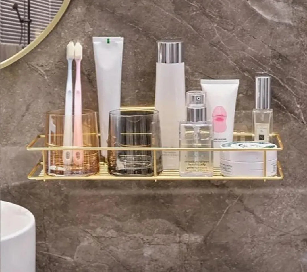 Gold wall-mounted bathroom rack holding toothbrushes, skincare bottles and toiletries