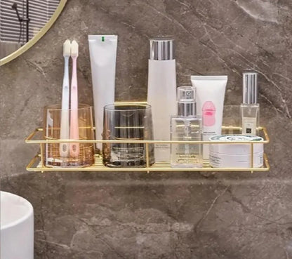 Gold wall-mounted bathroom rack holding toothbrushes, skincare bottles and toiletries