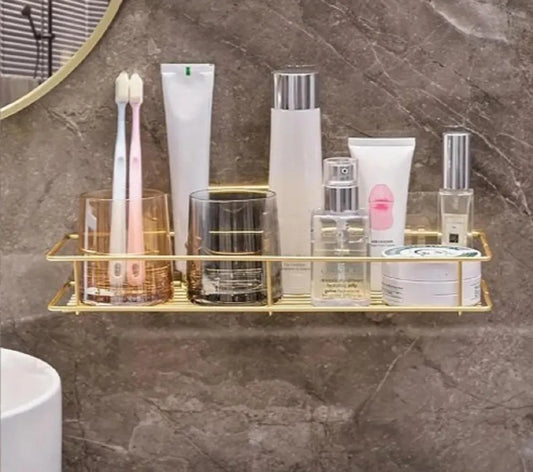 Gold wall-mounted bathroom rack holding toothbrushes, skincare bottles and toiletries