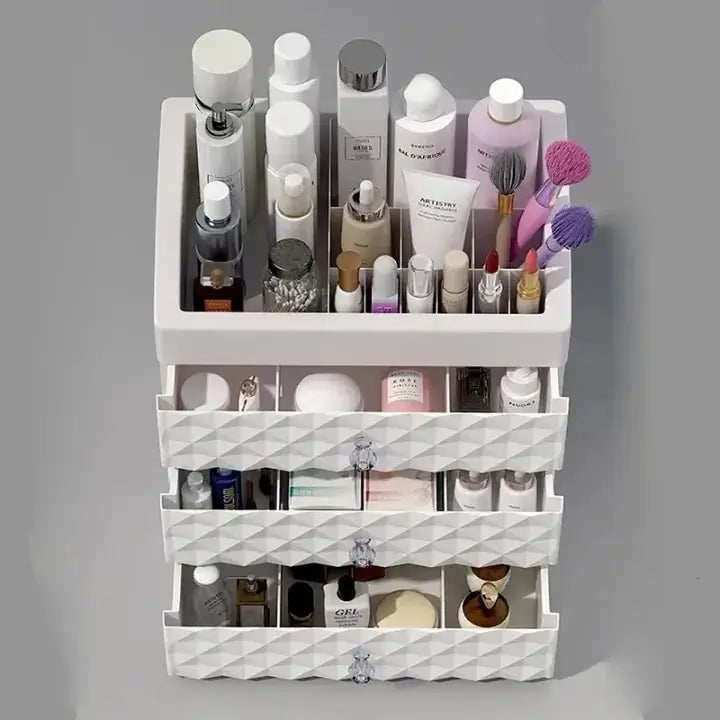 Front view of white makeup organizer showing top compartment and three partially open drawers