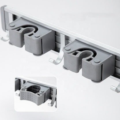 Close-up of anti-slip grip slots and hooks on wall-mounted mop and broom holder