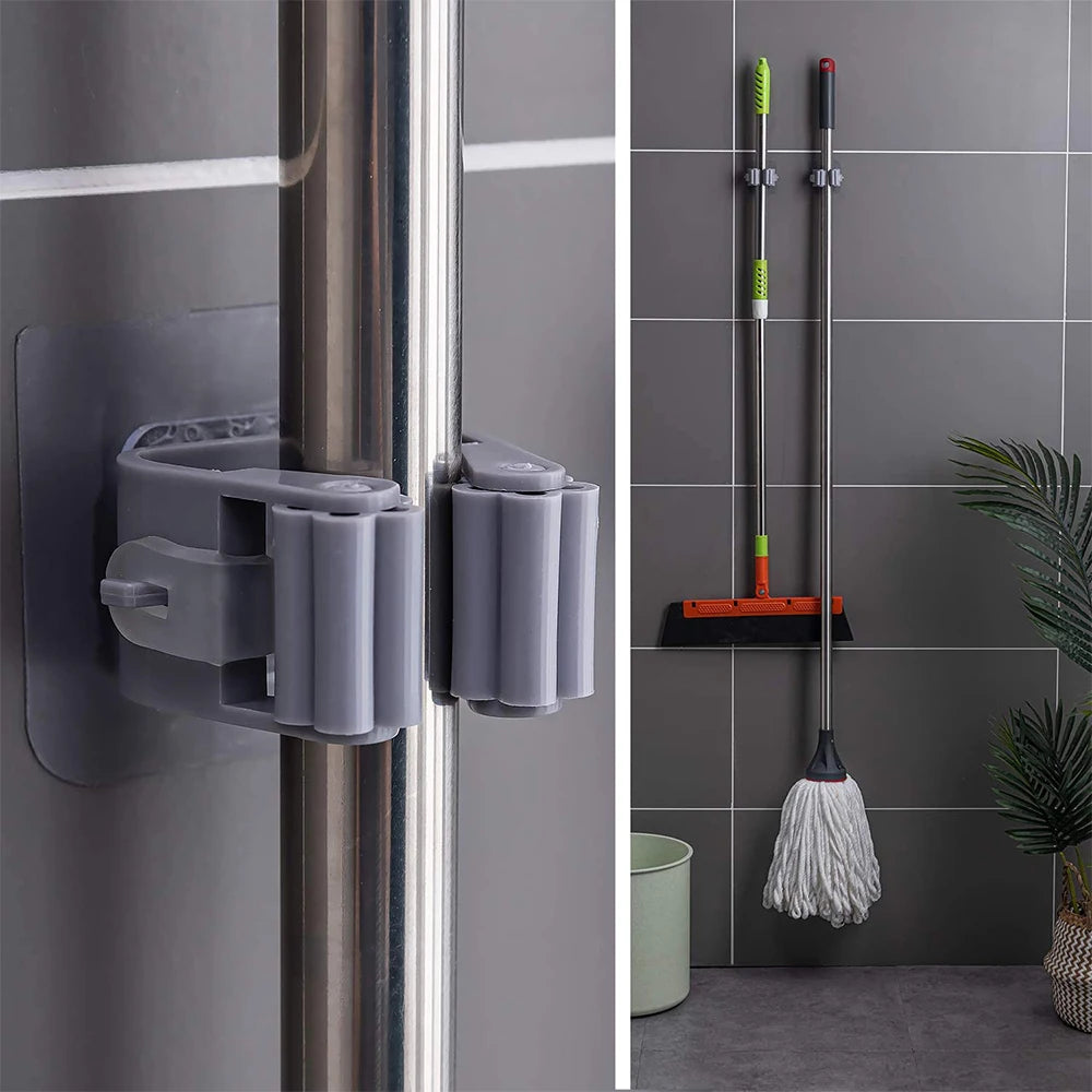 Close-up of a self-adhesive mop holder gripping cleaning-tool handles on a wall
