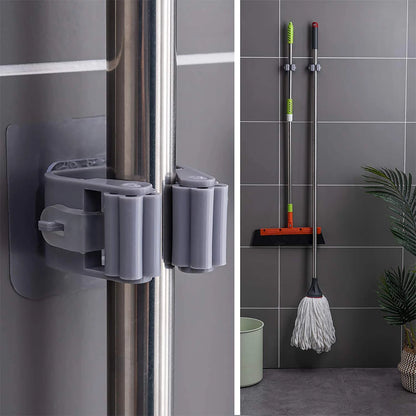 Close-up of a self-adhesive mop holder gripping cleaning-tool handles on a wall