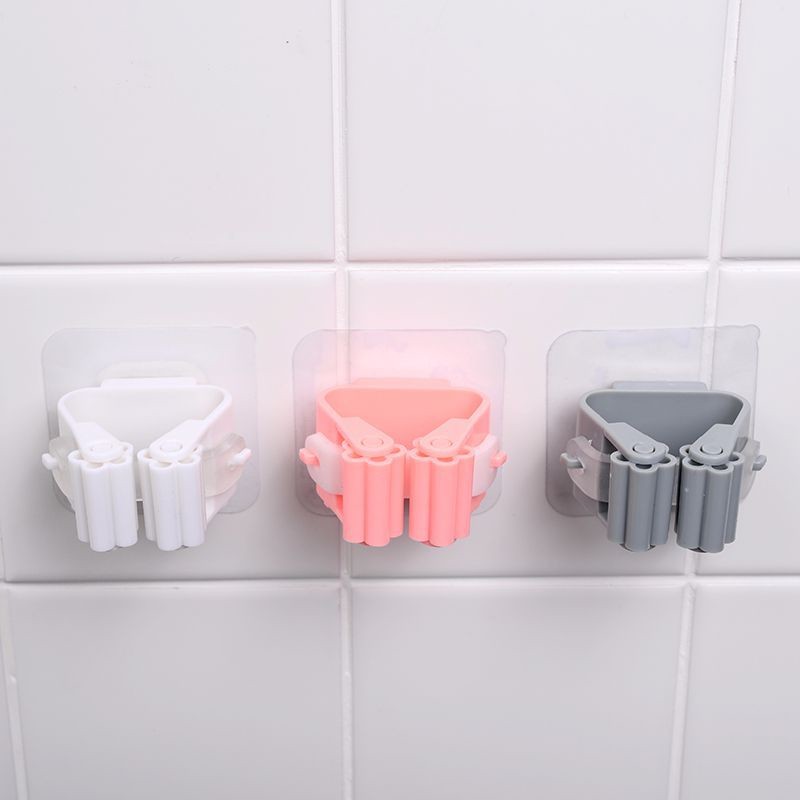 White, pink and grey self-adhesive mop and broom holders mounted on tiled wall