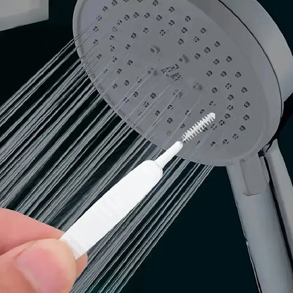 Mini cleaning brush being used to clean shower head nozzle holes